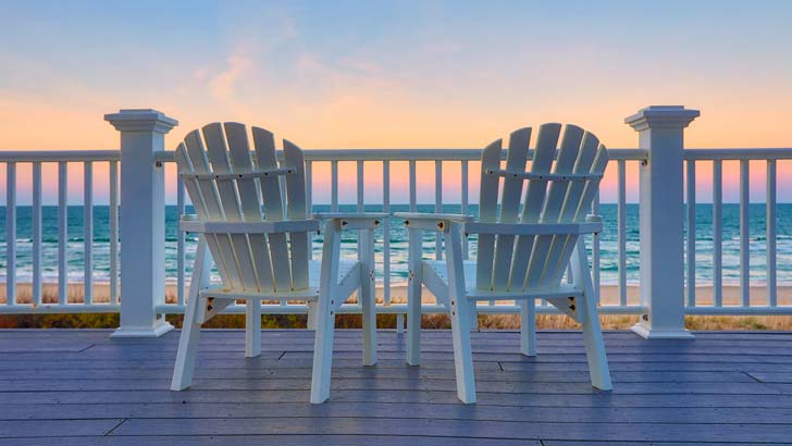 Sun chairs on balcony overlooking the beach at a holiday home.