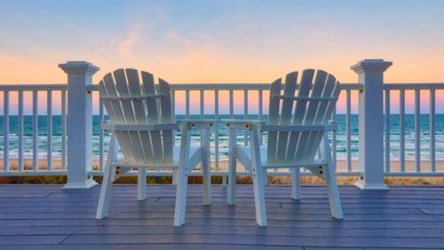 Sun chairs on balcony overlooking the beach at a holiday home.