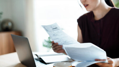 Australian woman looking stressed while reviewing household bills at her kitchen table