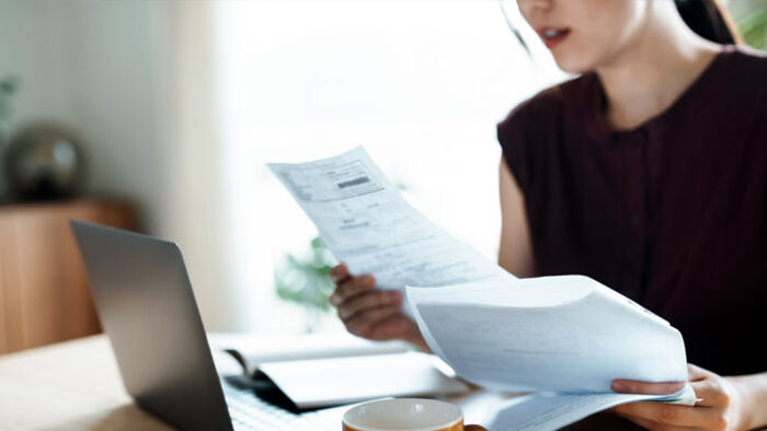 Australian woman looking stressed while reviewing household bills at her kitchen table