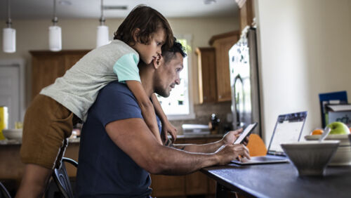 Man and child sitting together looking at a laptop at home, appearing focused on finances