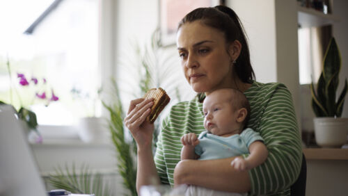 Woman looking concerned at paperwork and expenses while caring for family members
