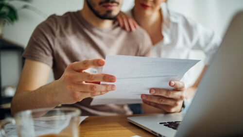 Australian adult looking stressed while reviewing unpaid bills at home