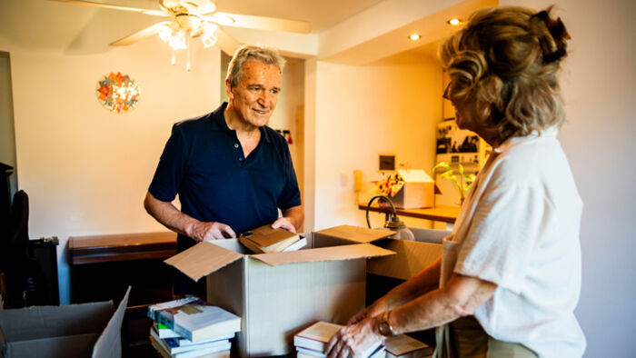 man and woman sorting through boxes at home and examining a potentially valuable item