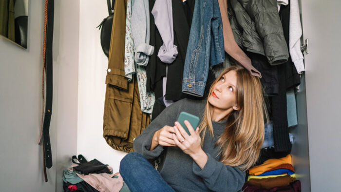 Clothes spilling from an overfilled wardrobe, illustrating overconsumption and textile waste.