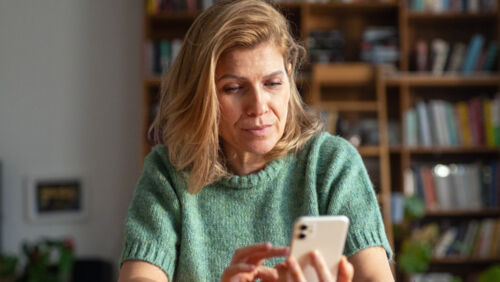 woman looking concerned at falling investment portfolio on phone