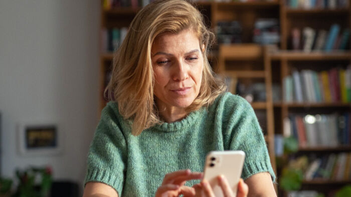 woman looking concerned at falling investment portfolio on phone