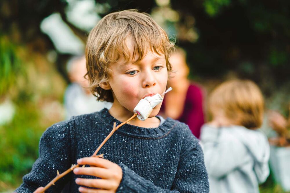 Children roasting marshmallows during a backyard camping adventure in the school holidays