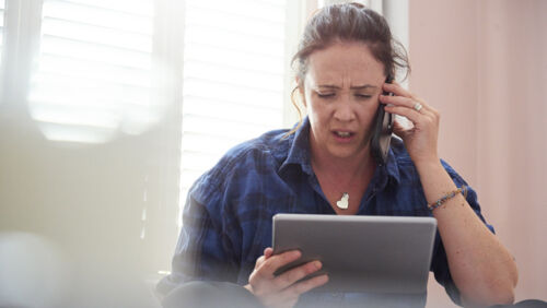 women looks at ipad and calls bank after missing a mortgage payment