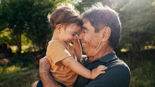a child and their grandfather embrace as experts advise parents teach their kids about money before they inherit wealth