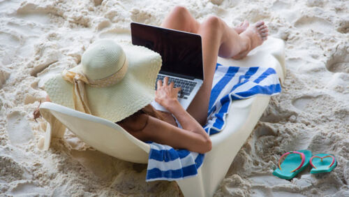 a woman works on the beach after boss forces her to take annual leave