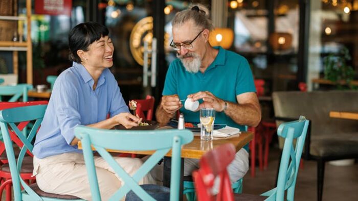 Retired couple enjoying coffee at a café while discussing their retirement plans