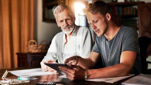 Adult son sitting beside his elderly father