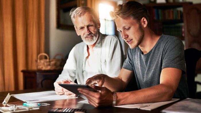 Adult son sitting beside his elderly father
