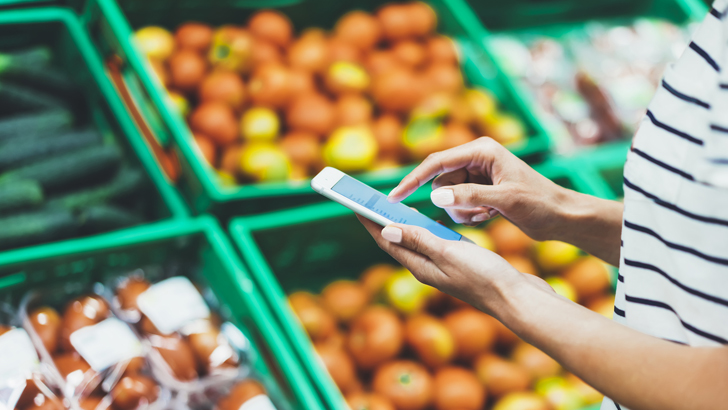 Person checking shopping list on phone, trying to save money on groceries while the cost of living rises in Australia.
